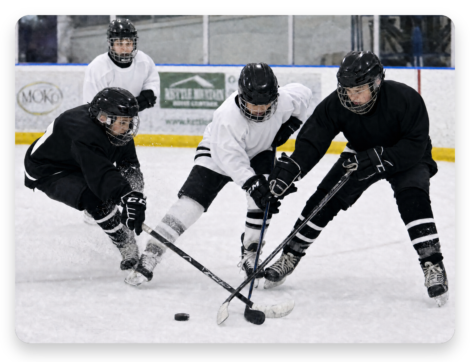 Players battling for the puck in a 3v3 cross-ice camp